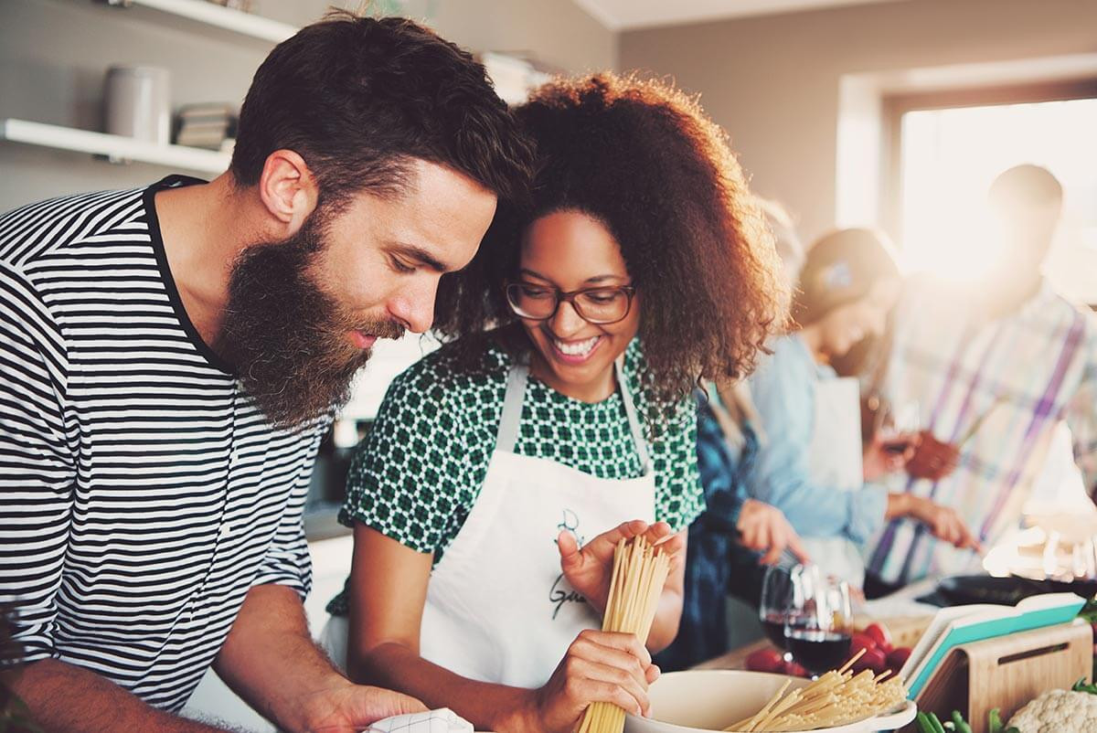 A woman and a man happily preparing food together in a bright kitchen, representing family eye care.