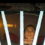 The Doctor in prison, marking tally marks on the wall, a humorous and poignant depiction of her isolation after the Timeless Children revelations.