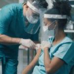 male doctor giving an injection to a female doctor