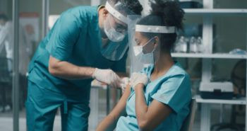 male doctor giving an injection to a female doctor